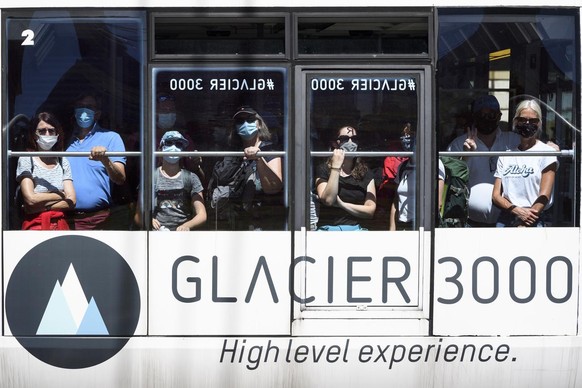 Tourists wearing protective mask ride a cable car of Glacier 3000 during the coronavirus disease (COVID-19) outbreak, in Les Diablerets, Switzerland, Monday, July 20, 2020. In Switzerland, from 6 July ...