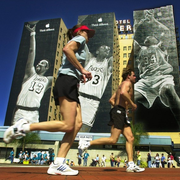 A pair of marathon runners pass by building-sized murals of Los Angeles Lakers stars, from left, Wilt Chamberlain, Kareem Abdul-Jabbar and Shaquille O&#039;Neal on Olympic Boulevard as they near the f ...