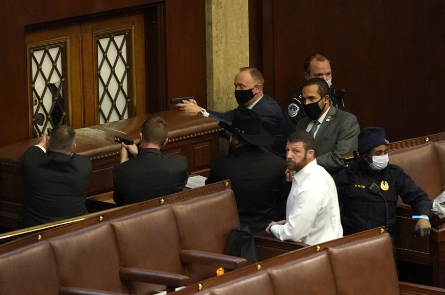 WASHINGTON, DC - JANUARY 06: U.S. Capitol police officers point their guns at a door that was vandalized in the House Chamber during a joint session of Congress on January 06, 2021 in Washington, DC.  ...