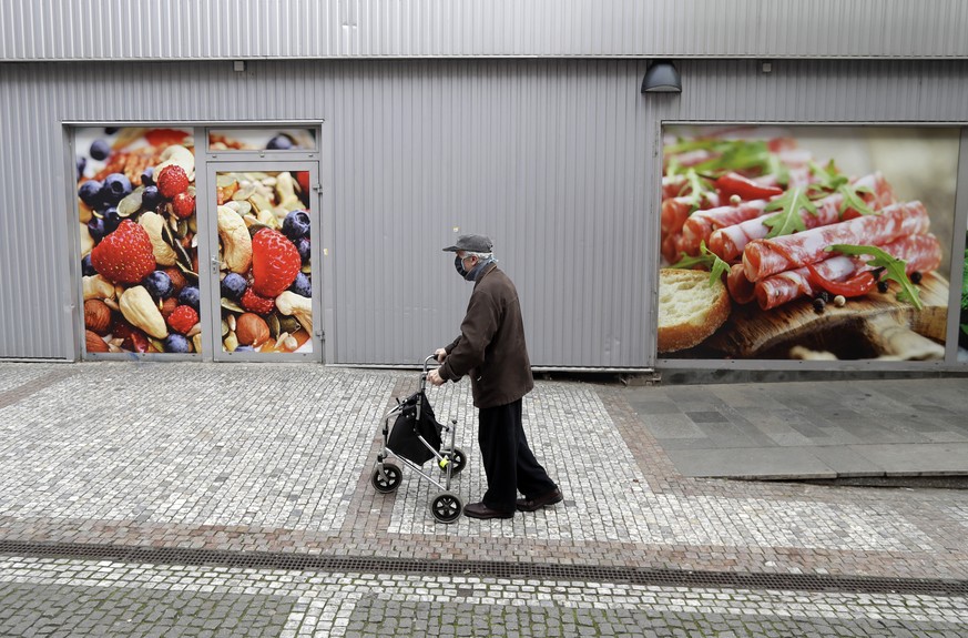 An elderly man walks to do his shopping at a grocery store in Prague, Czech Republic, Thursday, March 19, 2020. Due to the spread of the novel coronavirus called COVID-19 only people older than 65 yea ...