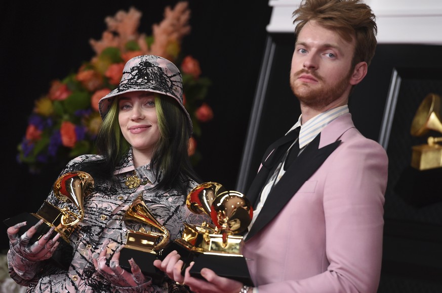 Finneas, right, and Billie Eilish pose in the press room with the awards for best song written for visual media and record of the year at the 63rd annual Grammy Awards at the Los Angeles Convention Ce ...