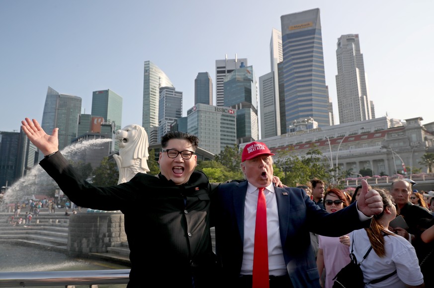 epa06792912 North Korean leader Kim Jong-un impersonator Howard (C-L) and US President Donald Trump impersonator Dennis (C) gesture while pictured against the Merlion statue and the skyline of the fin ...
