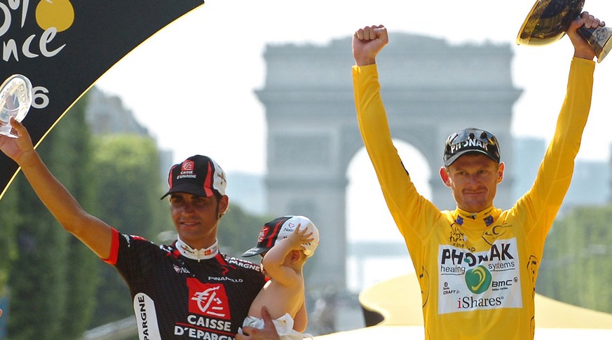 2006 Tour de France winner Floyd Landis of the U.S., right, holding his trophy, and second-placed Oscar Pereiro of Spain, left, with his child (no name available) wave from the podium after the final  ...