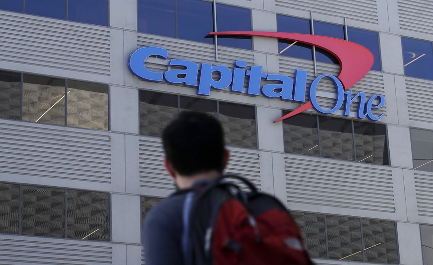 In this July 16, 2019, photo, a man walks across the street from a Capital One location in San Francisco. Capital One says a hacker got access to the personal information of over 100 million individua ...