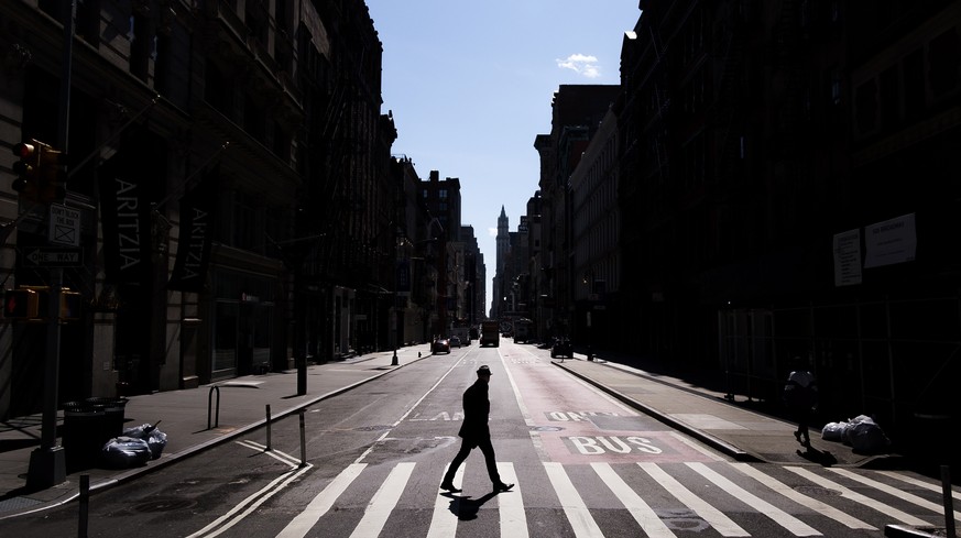 epa08346863 A person crosses a quiet Broadway, normally busy with shoppers and tourists on Monday, with the Chrysler building seen in the distance in New York, New York, USA, 06 April 2020. New York C ...