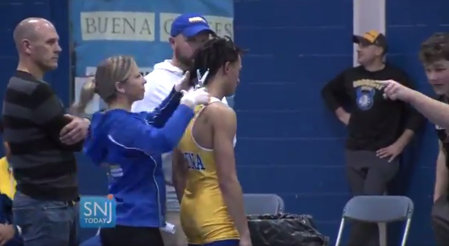 In this image taken from a Wednesday, Dec. 19, 2018 video provided by SNJTODAY.COM, Buena Regional High School wrestler Andrew Johnson gets his hair cut courtside minutes before his match in Buena, N. ...