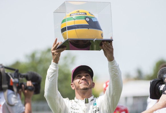 Mercedes driver Lewis Hamilton, of Great Britain, holds up a racing helmet of former F1 driver Ayrton Senna after winning pole position at the F1 Canadian Grand Prix auto race, Saturday, June 10, 2017 ...