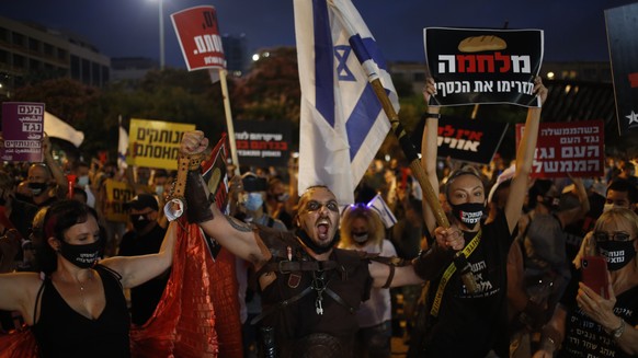 Protesters hold signs during a demonstration against Israel&#039;s government in Rabin square in Tel Aviv, Israel, Saturday, July 11, 2020. Thousands of Israelis gathered Saturday to protest the new g ...