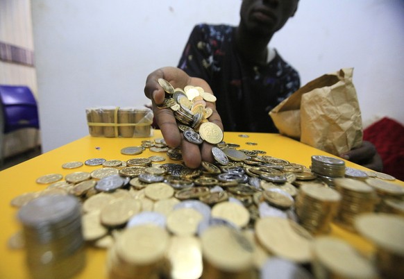 epa07978814 A vendor counts her small change in CFA currency at an Abidjan market, Ivory Coast, 07 November 2019. Small change is rare in Ivory Coast. A situation that is very often a source of inconv ...