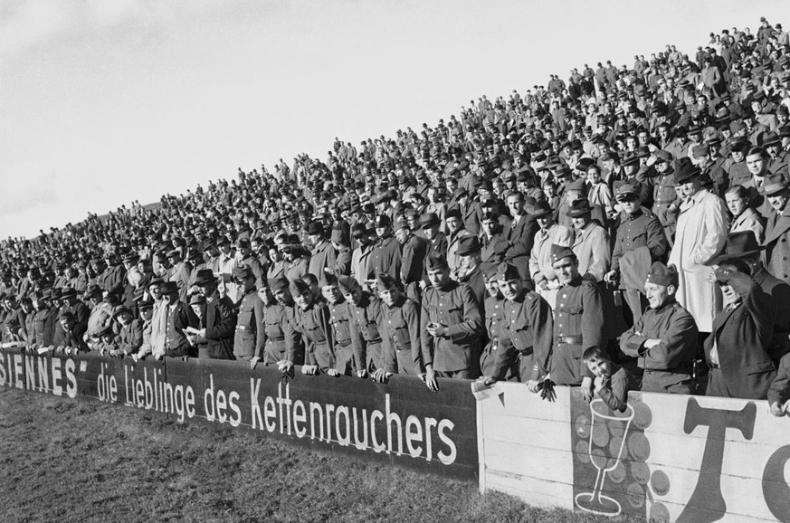 Zuschauer, darunter etliche Soldaten, verfolgen am 5. November 1939 im Wankdorf-Stadion in Bern hinter der Zigaretten-Bandenwerbung &quot;Parisiennes, die Lieblinge des Kettenrauchers&quot; ein Traini ...