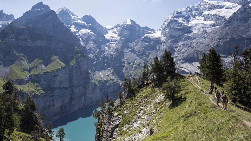 People walk around the lake of Oeschinen &quot;Oeschinensee&quot; (1578 meters above sea) and the mountains, above Kandersteg, in the Bernese Oberland, this Sunday, July 30, 2017. (KEYSTONE/Anthony An ...