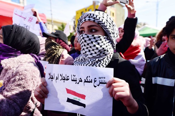 epa08215009 An Iraqi woman carries a place card reading in Arabic &#039;We will take away our freedom from you, sooner or later&#039; during a demonstration at the Al-Tahrir square in central Baghdad, ...