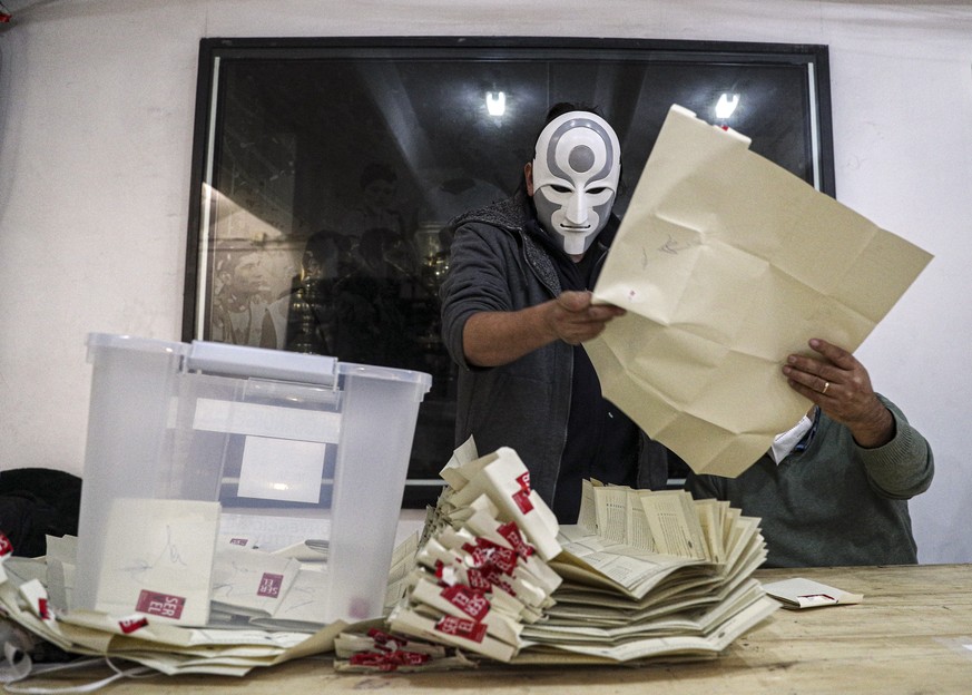An electoral worker with a mask of the Amon character of the Legend of Korra animated series counts ballots after the second day of the Constitutional Convention election to select assembly members th ...