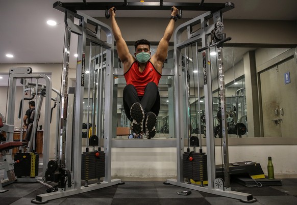 epa08775366 An Indian youth wearing a face mask works out in a gym in Mumbai, India, 26 October 2020. Following seven months of closures as part of the measures to fight the spread of COVID-19, from 2 ...