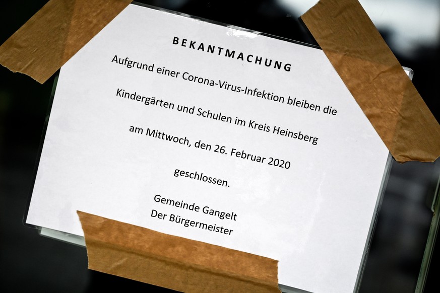 epa08248528 A sign reading ?Due to a corona virus infection, Kindergartens and schools in the district of Heinsberg will be closed on Wednesday 26 February 2020. The mayor of Gangelt? at the front doo ...