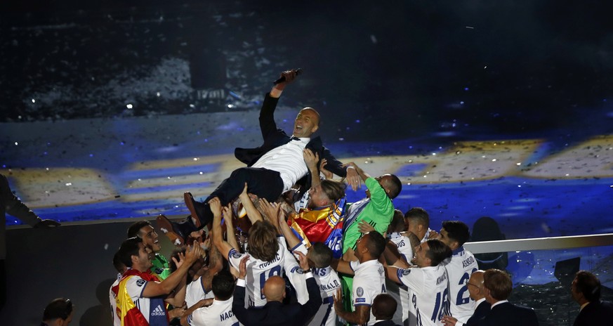 Real Madrid players lift head coach Zinedine Zidane into the air as they celebrate after winning the Champions League final, at the Santiago Bernabeu stadium in Madrid, Spain, Sunday, June 4, 2017. Re ...