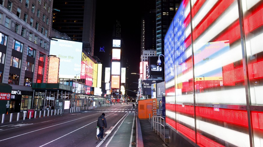 epa08323072 A person walks through a nearly empty Times Square in New York, USA, 25 March 2020. A statewide shut down of all non-essential businesses and a ban on all non-solitary outside activities i ...