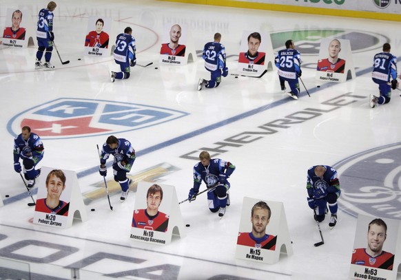 epa02904649 Players of hockey team Dinamo Minsk pay tribute in front of the portraits of Lokomotiv Yaroslavl hockey players in the Minsk-Arena stadium during a mourning ceremony in Minsk, Belarus, 08  ...