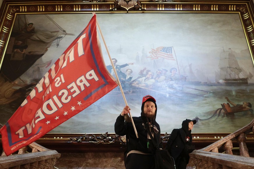 WASHINGTON, DC - JANUARY 06: A protester holds a Trump flag inside the US Capitol Building near the Senate Chamber on January 06, 2021 in Washington, DC. Congress held a joint session today to ratify  ...