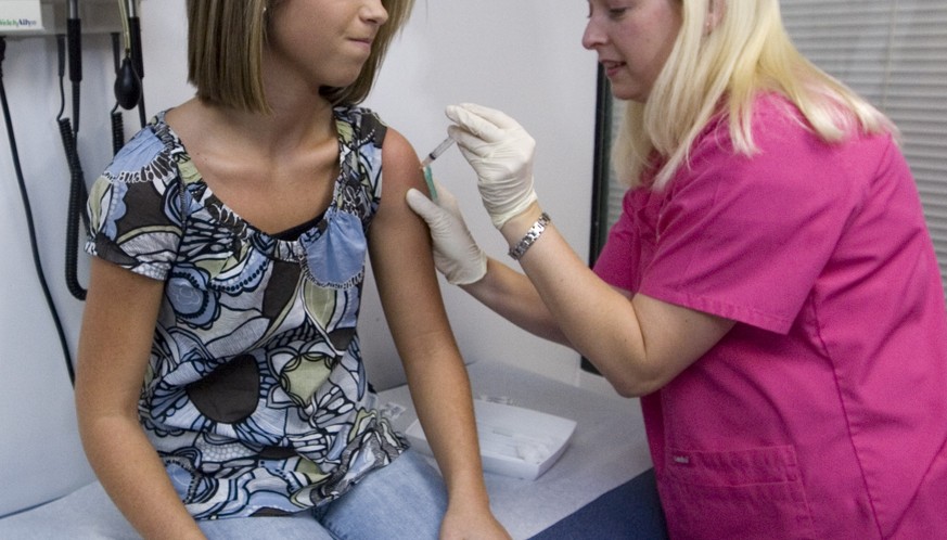 FILE - In this Dec. 18, 2007 file photo, Lauren Fant, left, winces as she has her third and final application of the Human Papillomavirus (HPV) vaccine administered by nurse Stephanie Pearson at a doc ...