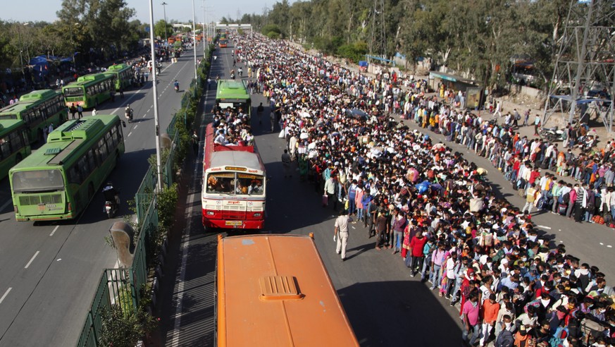 In this Saturday, March 28, 2020, file photo, Indian migrant laborers wait for buses provided by the government to transport them to their hometowns, following a lockdown amid concern over spread of c ...
