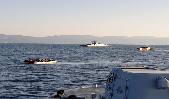 In this photo provided by the Hellenic Coast Guard and taken from a vessel shows a dinghy with migrants, left, with Turkish ships in the background, in the narrow stretch of water between the eastern  ...
