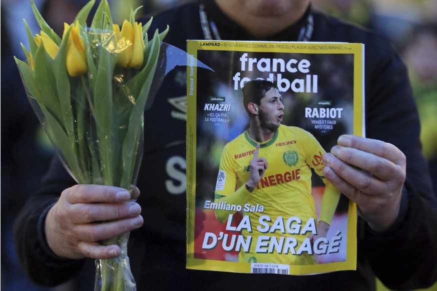 A FC Nantes soccer fan displays an old copy of French soccer magazine, France Football, featuring FC Nantes soccer player Emiliano Sala of Argentina, during a tribute in Nantes, western France, Tuesda ...