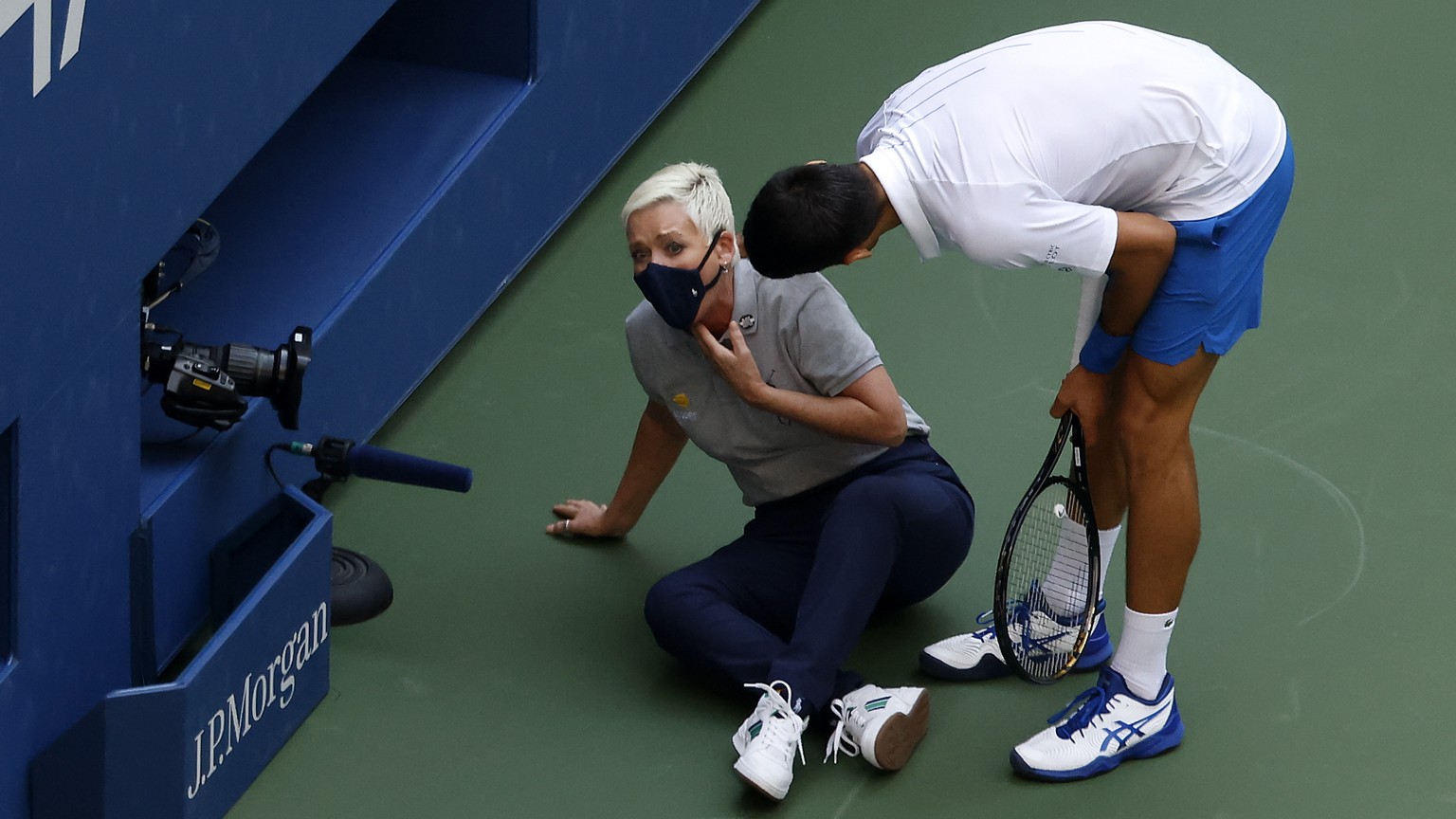 epa08651641 Novak Djokovic of Serbia (R) tries to help a linesperson after hitting her with a ball in the throat during his match against Pablo Carreno Busta of Spain on the seventh day of the US Open ...