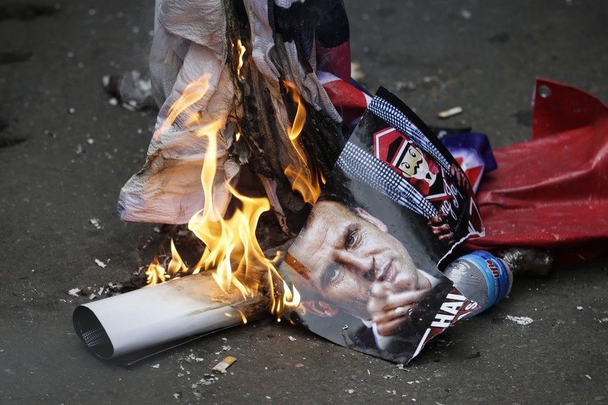 epa08792561 People burn a photo of French President Emmanuel Macron during a protest outside the French Embassy in Jakarta, Indonesia, 02 November 2020. The protest was held in response to Macron&#039 ...