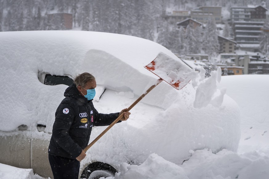 A member of Frensch ski team removes snow from a car with a shovel , in St. Moritz, Switzerland, Saturday, December 5, 2020. Due to a heavy snowfall and strong wind, the FIS decided to cancel today&#0 ...