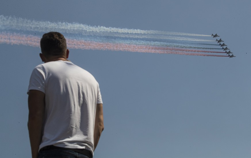 epa08497080 A man looks as Russian Army aircrafts fly above the Moscow Kremlin during the general rehearsal of the Victory Day parade in Moscow, Russia, 20 June 2020. The military parade marking the 7 ...