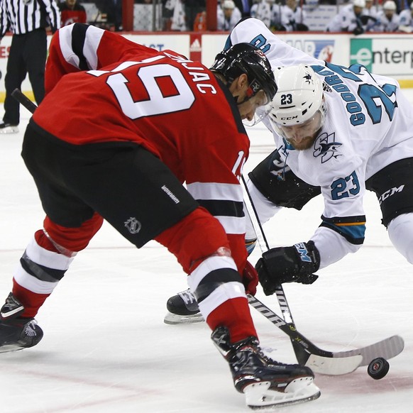 New Jersey Devils center Travis Zajac (19) and San Jose Sharks right wing Barclay Goodrow (23) face off during the first period of an NHL hockey game, Sunday, Oct. 14, 2018, in Newark,N.J. (AP Photo/  ...