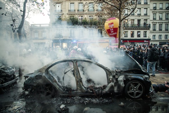 epa08849534 Firefighters extinguish a burned car as clashes erupt at Bastille Square after a demonstration against the newly passed controversial global security law, in Paris, France, 28 November 202 ...