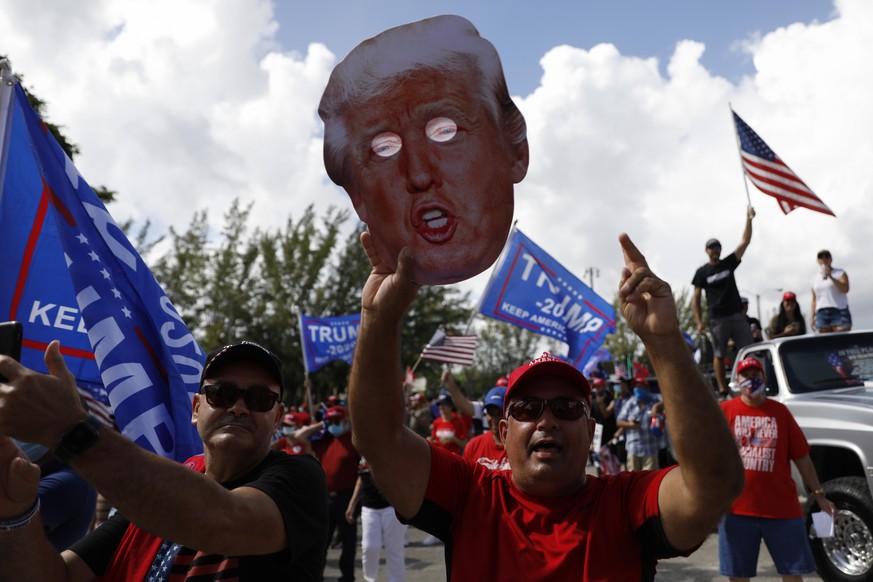 FILE - In this Nov. 1, 2020, file photo, a man holds up a cardboard cutout of President Donald Trump as supporters rally ahead of the start of a car caravan by hundreds of vehicles, at Tropical Park i ...