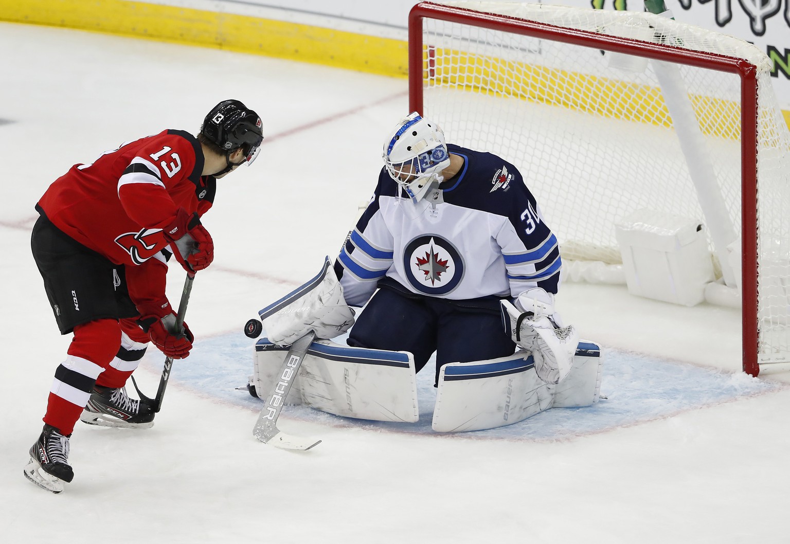 Winnipeg Jets goaltender Laurent Brossoit (30) makes a save against New Jersey Devils center Nico Hischier (13) during the third period of an NHL hockey game Friday, Oct. 4, 2019, in Newark, N.J. (AP  ...