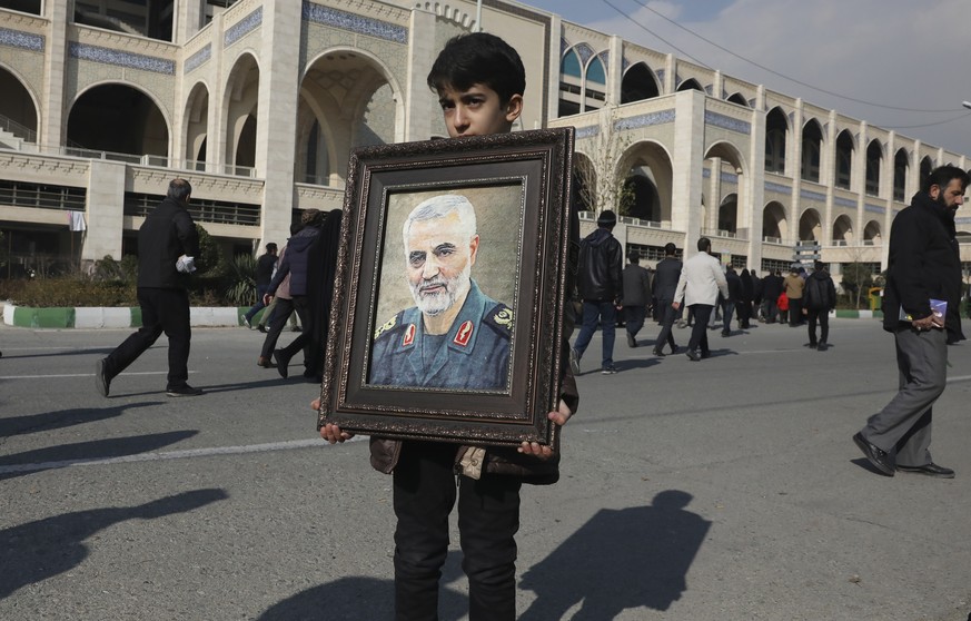 A boy carries a portrait of Iranian Revolutionary Guard Gen. Qassem Soleimani, who was killed in the U.S. airstrike in Iraq, prior to the Friday prayers in Tehran, Iran, Friday Jan. 3, 2020. Iran has  ...