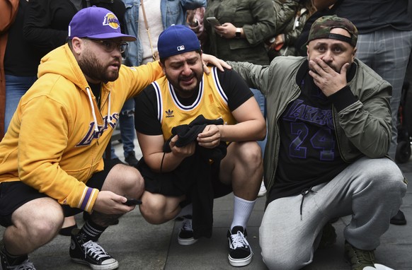 Los Angeles Lakers fans Alex Fultz, from left, Eddy Rivas and Rene Alfaro react to the death of former NBA player Kobe Bryant outside of the Staples Center prior to the 62nd annual Grammy Awards on Su ...