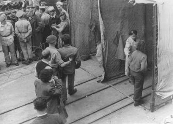 Britische Soldaten zwingen jüdische Flüchtlinge vom Schiff Theodor Herzl durch eine Desinfektionsstation, bevor sie in Internierungslager auf Zypern deportiert werden, im Hafen von Haifa, Palästina, 2 ...
