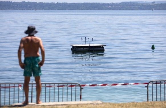 Ein Mann schaut auf den mit Absperrbaendern geschlossenen Strand bei Boudry, am Freitag, 31. Juli 2020 in Boudry am Neuenburgersee. Die Behoerden im Kanton Neuenburg haben ein Badeverbot fuer den Stra ...