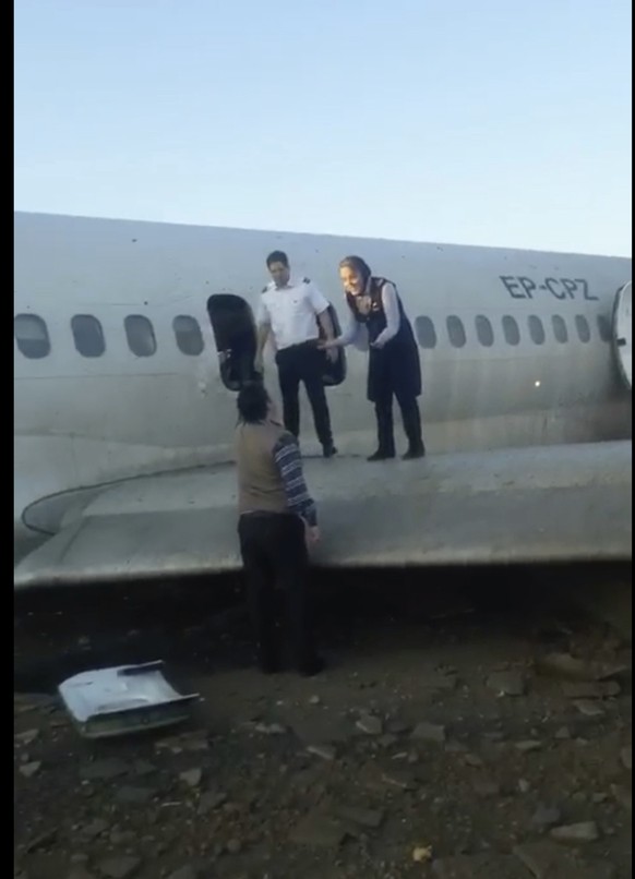 In this image from video shot by Iran&#039;s Civil Aviation Network News, a flight attendant speaks to an onlooker as passengers walk off over the wing of a crashed plane in Mahshahr, Iran, Monday, Ja ...