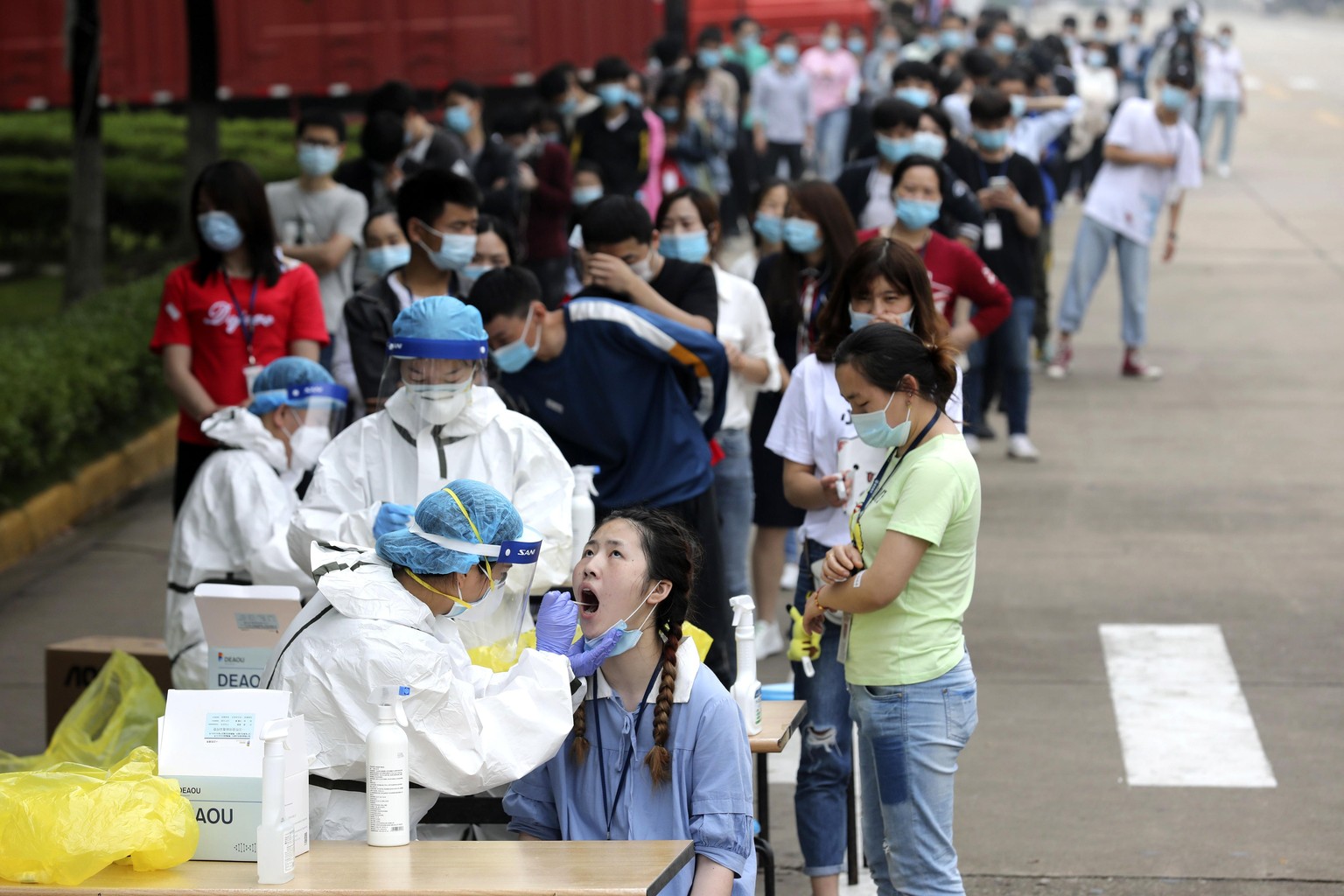 Workers line up for medical workers to take swabs for the coronavirus test at a large factory in Wuhan in central China&#039;s Hubei province Friday, May 15, 2020. Wuhan have begun testing inhabitants ...