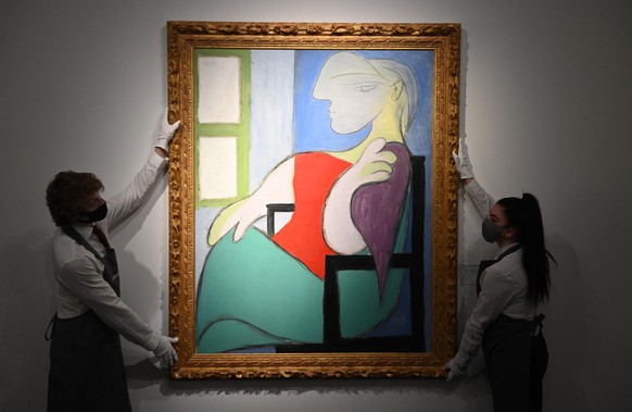 epa09152178 Art handlers pose with the work &#039;Femme assise pres d&#039;une fenetre (Marie-Therese)&#039; by Pablo Picasso (L) and &#039;Composition: No. II, with Yellow, Red and Blue&#039; by Piet ...