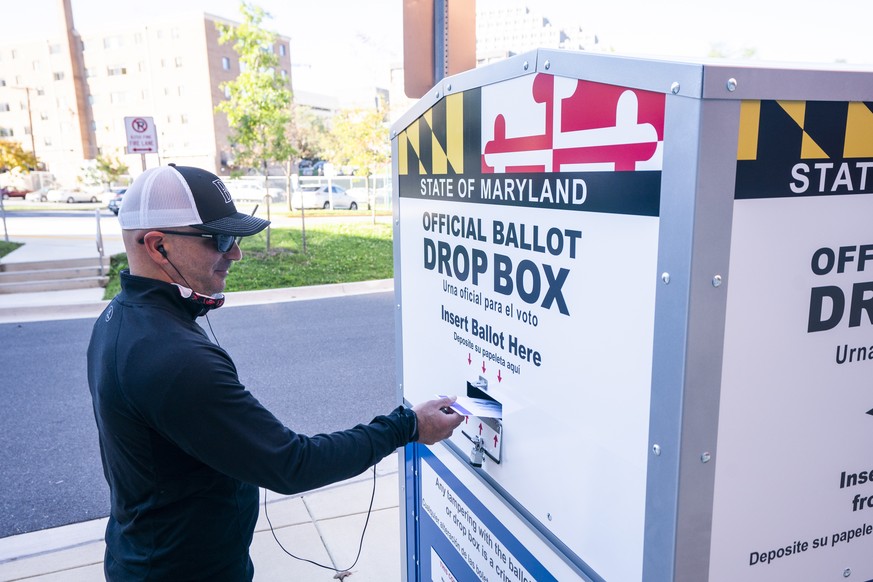 epa08747849 A Maryland resident drops off his completed ballot for the 2020 presidential election at an official ballot drop box in Bethesda, Maryland, USA, 15 October 2020. The 2020 presidential elec ...