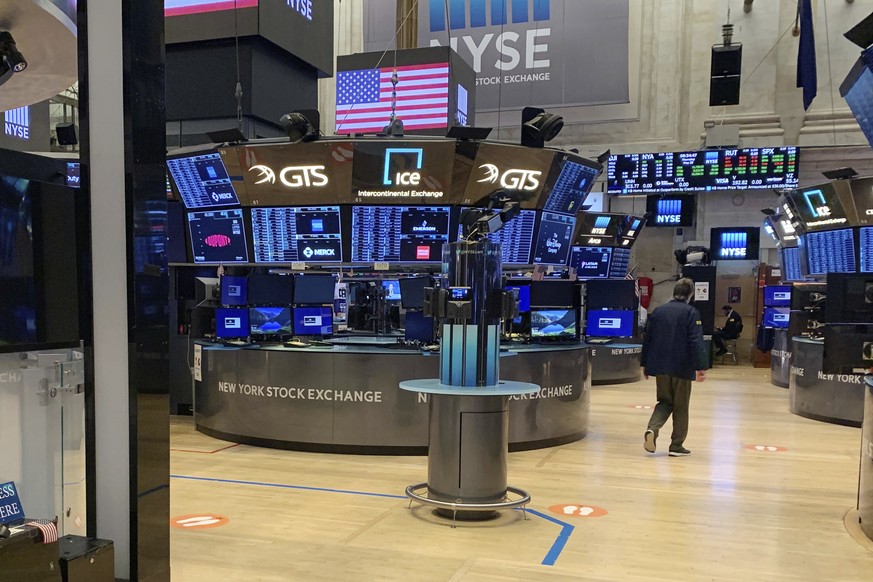 A trader walks across the partially reopened trading floor of the New York Stock Exchange, Thursday, May 28, 2020. Stocks are pushing higher in morning trading on Wall Street Thursday, extending this  ...