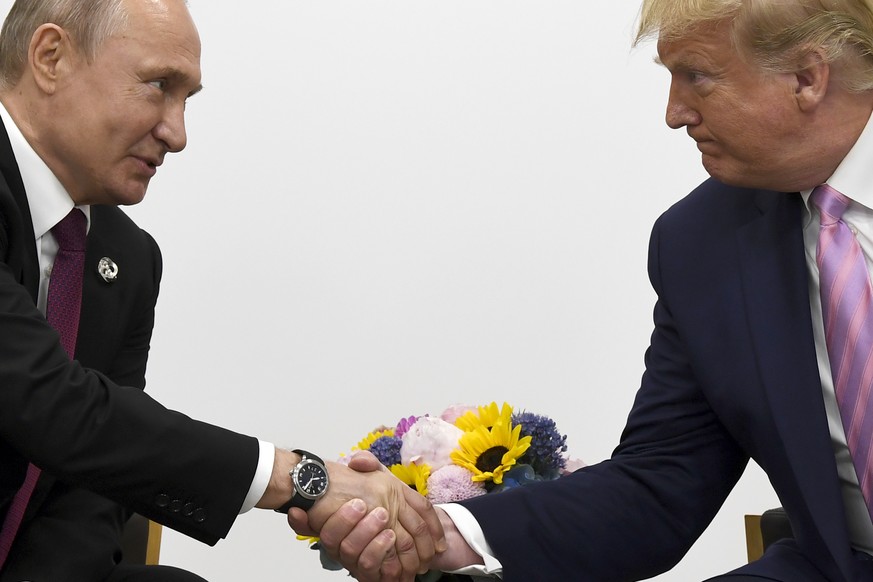 FILE - In this file photo taken on Friday, June 28, 2019, President Donald Trump, right, shakes hands with Russian President Vladimir Putin during a bilateral meeting on the sidelines of the G-20 summ ...