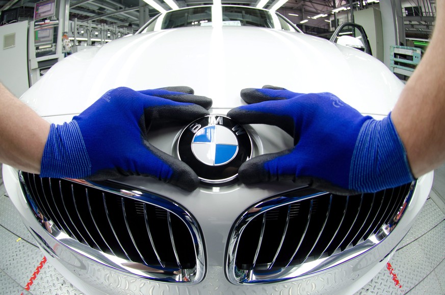 epa04475551 (FILE) A file photo dated 07 March 2012 showing an employee attaching a BMW logo onto the hood of a new car at the factory in Regensburg, Germany. Luxury carmaker BMW reported 04 November  ...