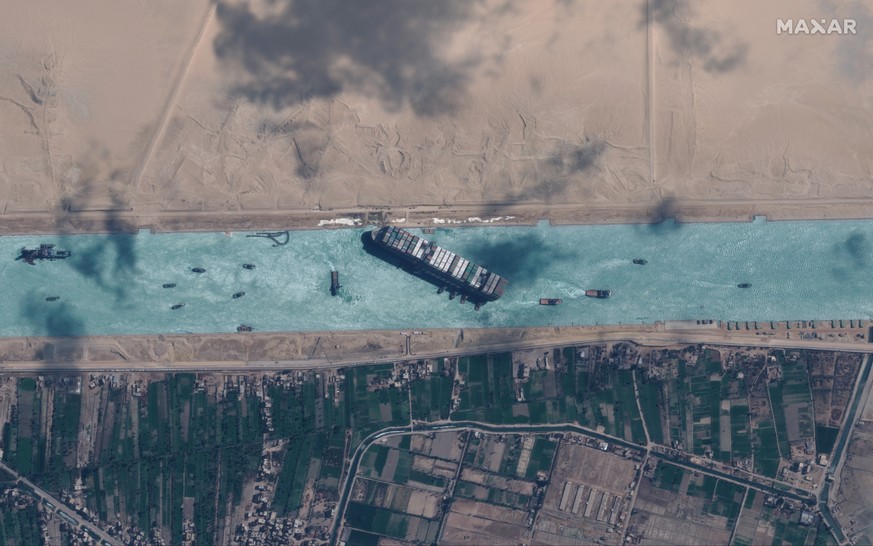 epa09105217 A handout satellite image made available by MAXAR Technologies shows , the Ever Given container ship after it has been moved away from the eastern bank of the canal and tugboats trying to  ...