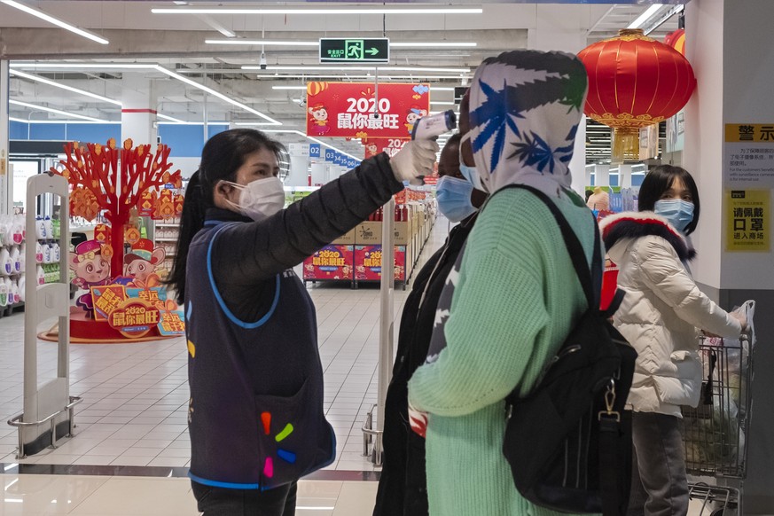 In this Monday, Jan. 27, 2020 photo, a worker takes the temperature of a customer at the entrance of a Walmart store in Wuhan in central China&#039;s Hubei Province. China&#039;s death toll from a new ...