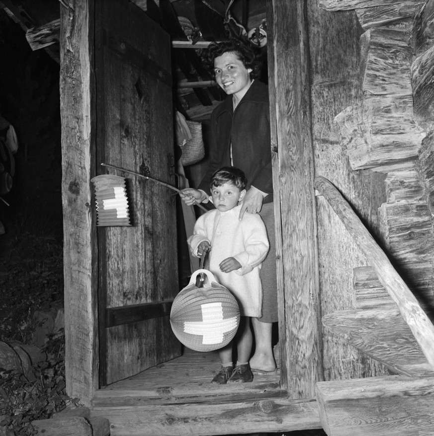 Kleines Kind und Mutter mit Lampions in der Tuer ihres Hauses an der Bundesfeier in Grimentz im Val d&#039;Anniviers, aufgenommen am 1. August 1956. (KEYSTONE/PHOTOPRESS-ARCHIV/Alain