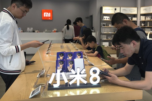 In this Wednesday, June 20, 2018, photo, People try out the Xiaomi latest smartphones on display at the Xiaomi store in Beijing, Wednesday, June 20, 2018. Xiaomi, a Chinese startup that helped to pion ...
